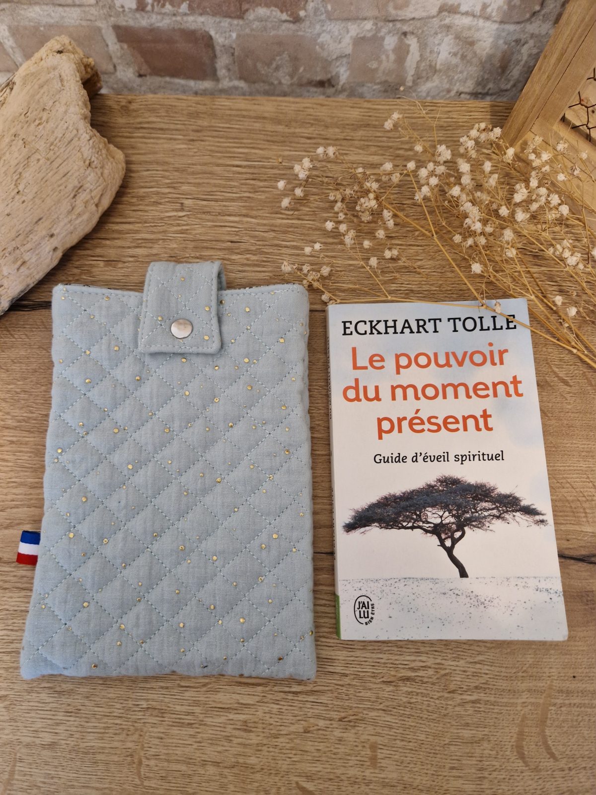 Cette pochette molletonnée avec des tissus uni est un accessoire utile pour ranger votre livre du moment. Tout en coton et molletonné pour une protection optimale, elle convient au format livre de poche classique. Ferme avec un bouton de pression. Ainsi vous pourrez le glisser dans votre sac sans abimer les angles.