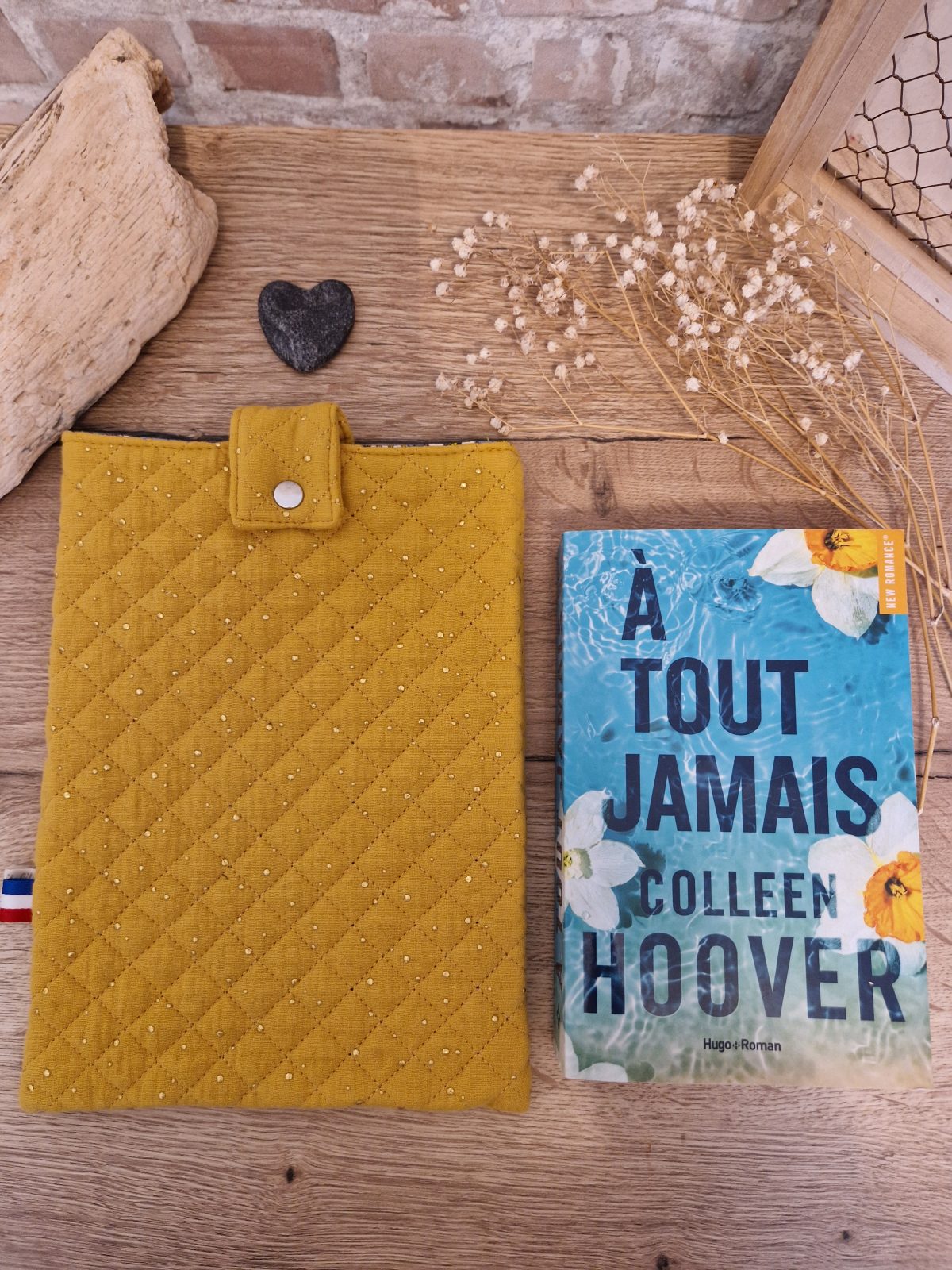 Cette pochette molletonnée avec des tissus uni est un accessoire utile pour ranger votre livre du moment. Tout en coton et molletonnée pour une protection optimale, elle convient au format livre broché classique. Ferme avec un bouton de pression.